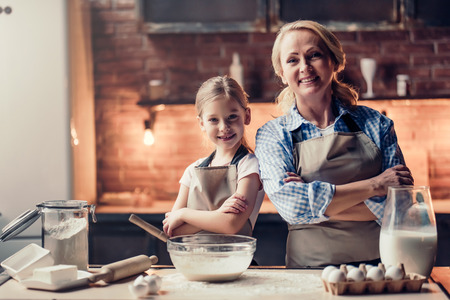 Grandmother and granddaughter are cooking on kitchen. Making tasty baking together.の写真素材