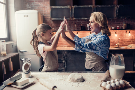 Grandmother and granddaughter are cooking on kitchen. Making tasty baking together.の写真素材