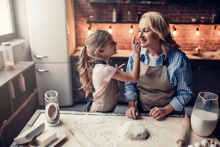 Grandmother and granddaughter are cooking on kitchen. Making tasty baking together.の写真素材