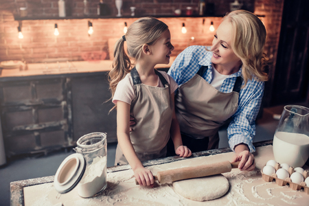 Grandmother and granddaughter are cooking on kitchen. Making tasty baking together.の写真素材
