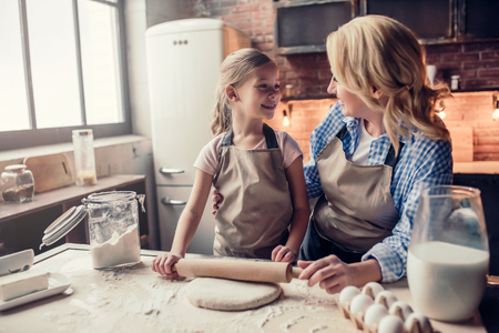 Grandmother and granddaughter are cooking on kitchen. Making tasty baking together.の写真素材