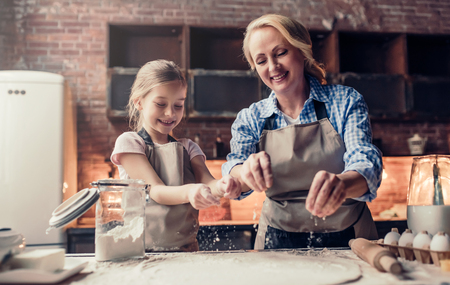 Grandmother and granddaughter are cooking on kitchen. Making tasty baking together.の写真素材
