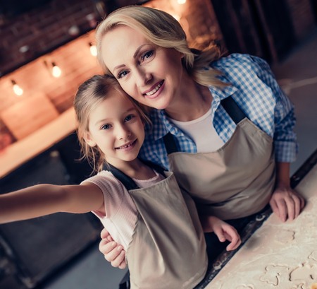 Grandmother and granddaughter are making selfie while cooking on kitchen. Making tasty baking together.の写真素材