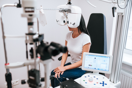 Attractive young woman is checking the eye vision in modern clinic. Patient in ophthalmology clinicの写真素材