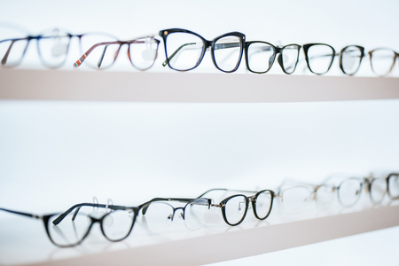 Big choice of eyeglasses on shelves in ophthalmology clinic. Modern light ophthalmology clinic.の写真素材