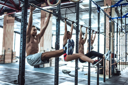 Group of sporty muscular people are working out in gym. Cross fit training. Hovering and doing abs exercise.の写真素材