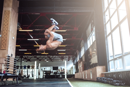Strong muscular man is working out in gym. Cross fit training. Doing a flip.の写真素材