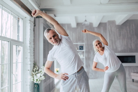 Senior couple is doing fitness training at home. Doing yoga together. Healthy lifestyle concept.の写真素材