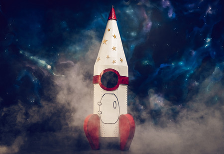 Toy rocket is standing on space background with smoke at the bottom.の写真素材