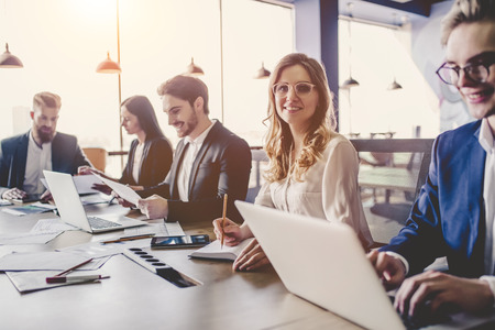 Group of young business people are working together in modern office with laptop, tablet, smart phone, notebook. Successful team in coworking. Freelancers.の写真素材