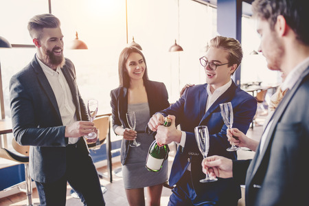 Group of young business people are working together in modern office. Successful team in coworking are celebrating event with champagne. Freelancers.の写真素材