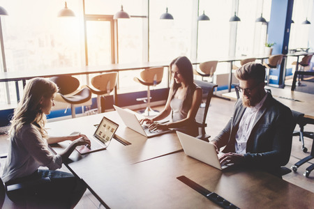 Group of young business people are working together in modern office with laptop, tablet, smart phone, notebook. Successful team in coworking. Freelancers.の写真素材