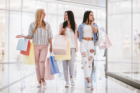 Three attractive young girls are doing shopping with shopping bags in modern mall.の写真素材