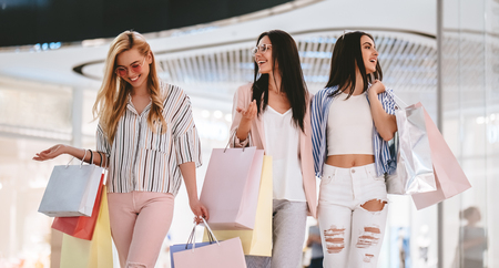 Three attractive young girls are doing shopping with shopping bags in modern mall.の写真素材