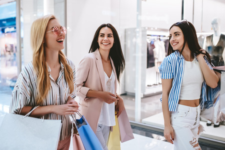 Three attractive young girls are doing shopping with shopping bags in modern mall.の写真素材