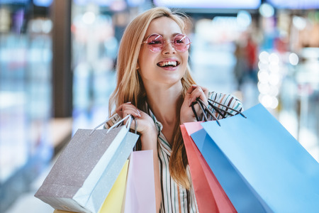 Attractive young happy woman is doing shopping with shopping bags in modern mall.の写真素材