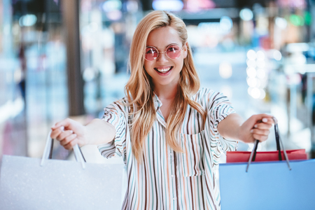 Attractive young happy woman is doing shopping with shopping bags in modern mall.の写真素材