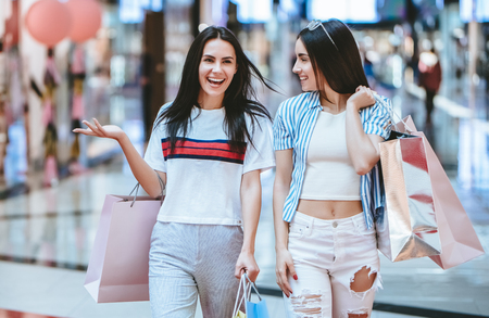 Two attractive young girls are doing shopping with shopping bags in modern mall.の写真素材