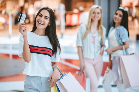 Three attractive young girls are doing shopping with shopping bags in modern mall.の写真素材