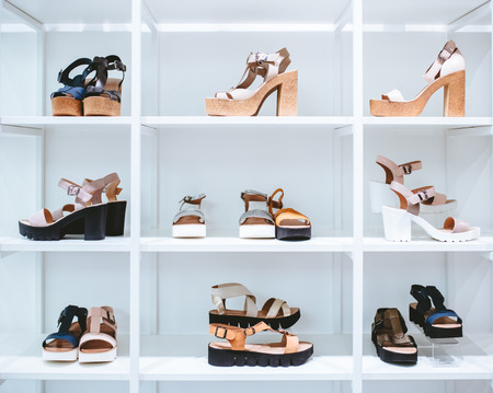 White rack in shoes store. Different kinds of women shoes are on sale in modern shoes store.の写真素材