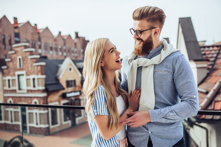 Young stylish happy couple is spending time together outdoors. Attractive woman and handsome bearded man are having fun together in the city.の写真素材