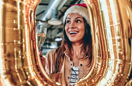 Merry Christmas and Happy New Year 2020!Young creative people are celebrating holiday in modern office. Young business woman is drinking champagne in coworking. Successful hipster team of freelancers.の写真素材