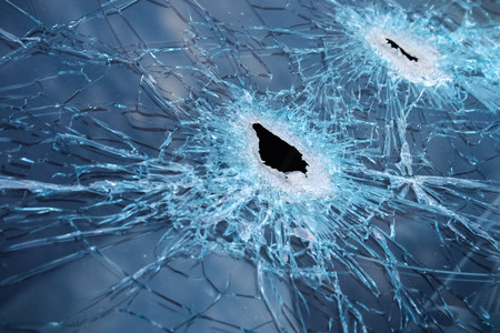 Closeup of a whole and cracked windshield produced by gunshotsの写真素材