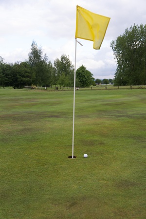golf ball close to a hole with the flag in placeの写真素材