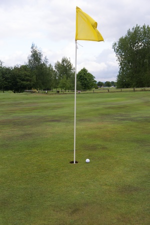 golf ball close to a hole with the flag in placeの写真素材