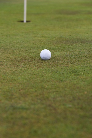 golf ball close to a hole with the flag in placeの写真素材