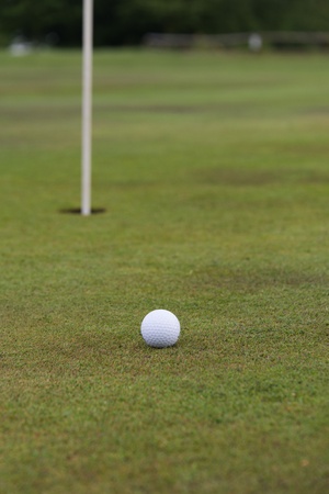 golf ball close to a hole with the flag in placeの写真素材