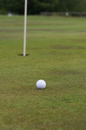 golf ball close to a hole with the flag in placeの写真素材
