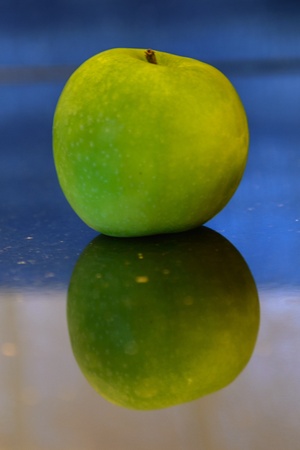 Green apple with reflection on a black granite work topの写真素材