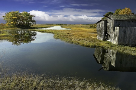 as the tides move in and out of the marsh lands, reflecions of the shack on the lands, shimmers in...