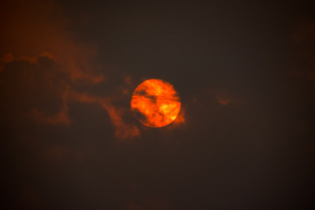 red sun behind cloudsの写真素材