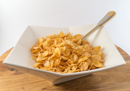 Bowl with corn cereals on wooden tableの写真素材