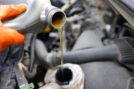 Car mechanic pouring oil into a car engine. Close-up.の写真素材