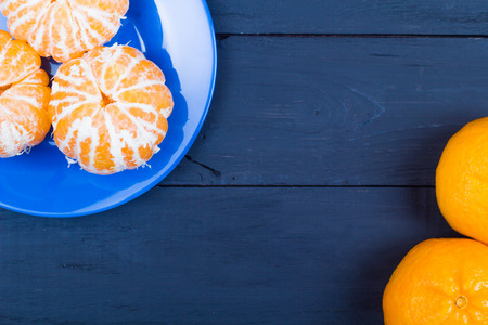 The tangerines peeled in a blue plate on a black tableの写真素材