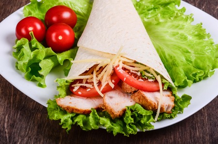 Burito on a white plate on a table of dark woodの写真素材