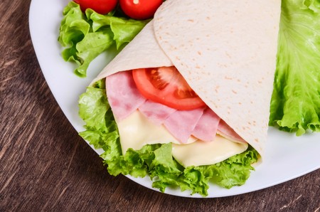 Burito on a white plate on a table of dark woodの写真素材