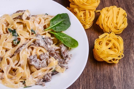 Pasta on a white plate on dark woodの写真素材