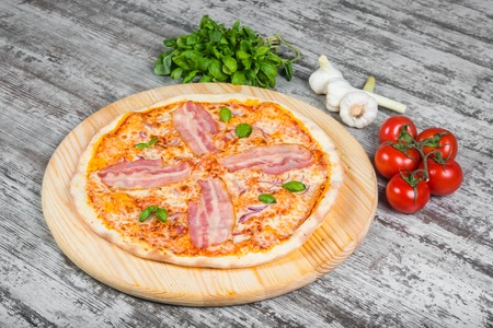 Italian pizza on a light wooden table on the background of vegetables and greensの写真素材