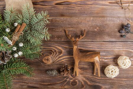 Wreath. Christmas winter frame on dark wooden background. Fir cones and cotton. Wooden toy deerの写真素材