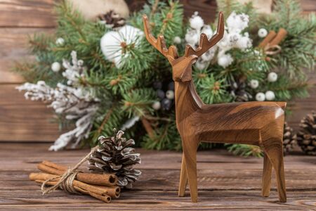 Wreath. Christmas winter frame on dark wooden background. Fir cones and cotton. Wooden toy deerの写真素材