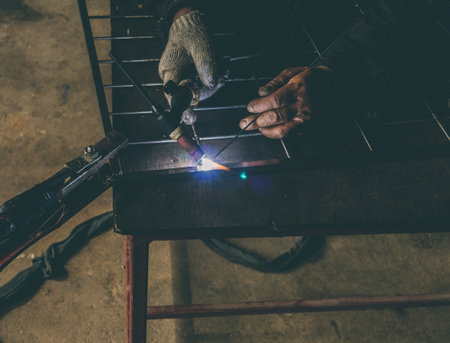 Close up portrait view of professional mask protected welder 
man in uniform working.の写真素材
