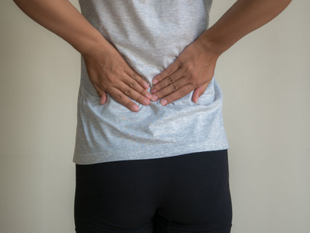 Woman suffering from back pain on gray background. Health care and medical concept.