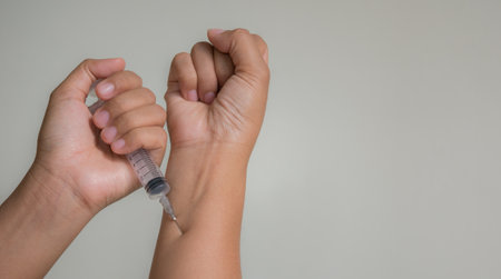 Woman hand holding a syringe on gray background. Vaccination conceptの写真素材