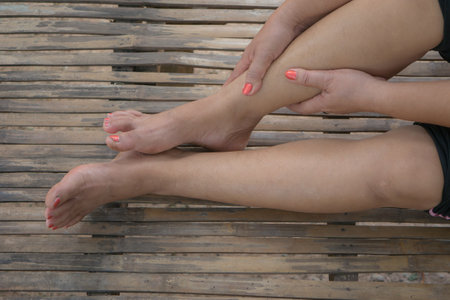 Female legs with red nail polish on the wooden background. Skin care concept.の写真素材