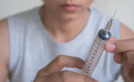 Close up of a syringe in hand of a young man.の写真素材