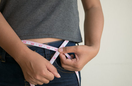 Woman measuring waist with tape measure. Diet and healthy lifestyle concept.の写真素材